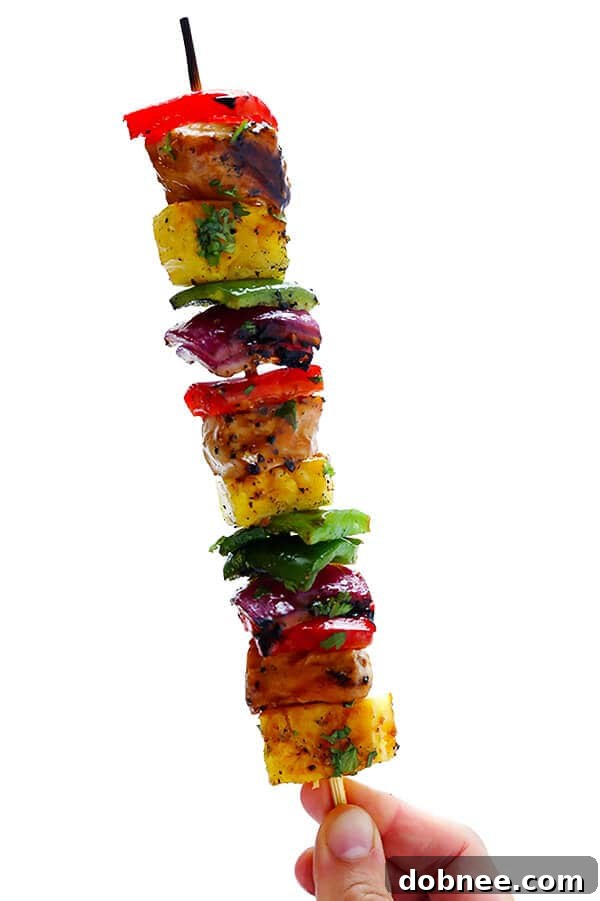 A plate of Rainbow Hawaiian Chicken Kabobs served with rice and garnished with cilantro, showcasing a perfect summer meal.