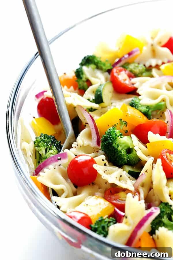 Delicious Veggie Lovers' Pasta Salad being tossed with white balsamic vinaigrette to ensure even flavor distribution.