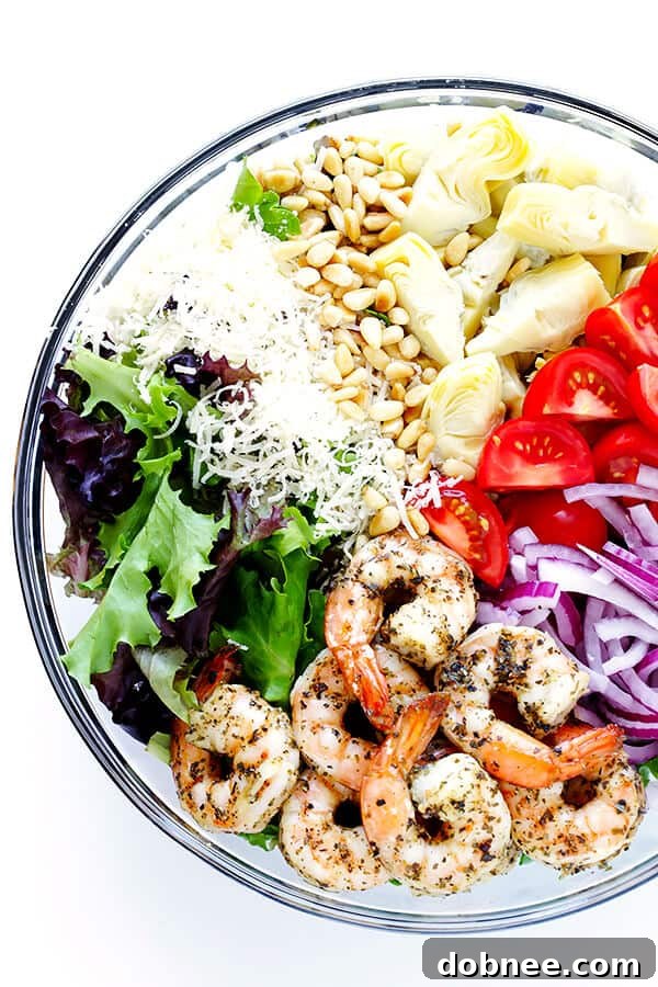 Close-up of the delightful Shrimp and Artichoke Green Salad, showcasing the perfectly cooked Italian-herb shrimp, vibrant tomatoes, fresh spring greens, and savory artichoke hearts, all glistening with the bright lemon vinaigrette. A truly irresistible and healthy meal idea.