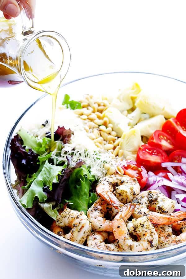The final step: Drizzling the zesty homemade lemon vinaigrette generously over the freshly tossed Shrimp and Artichoke Green Salad, ensuring every ingredient is perfectly coated and ready to deliver an explosion of fresh flavors. A delicious and healthy meal ready to enjoy!