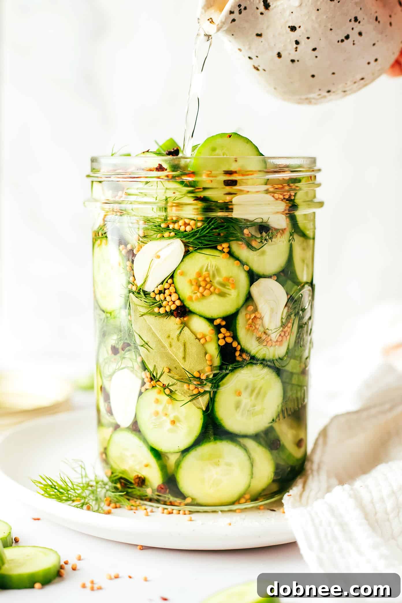 Four jars of homemade pickles lined up in a refrigerator