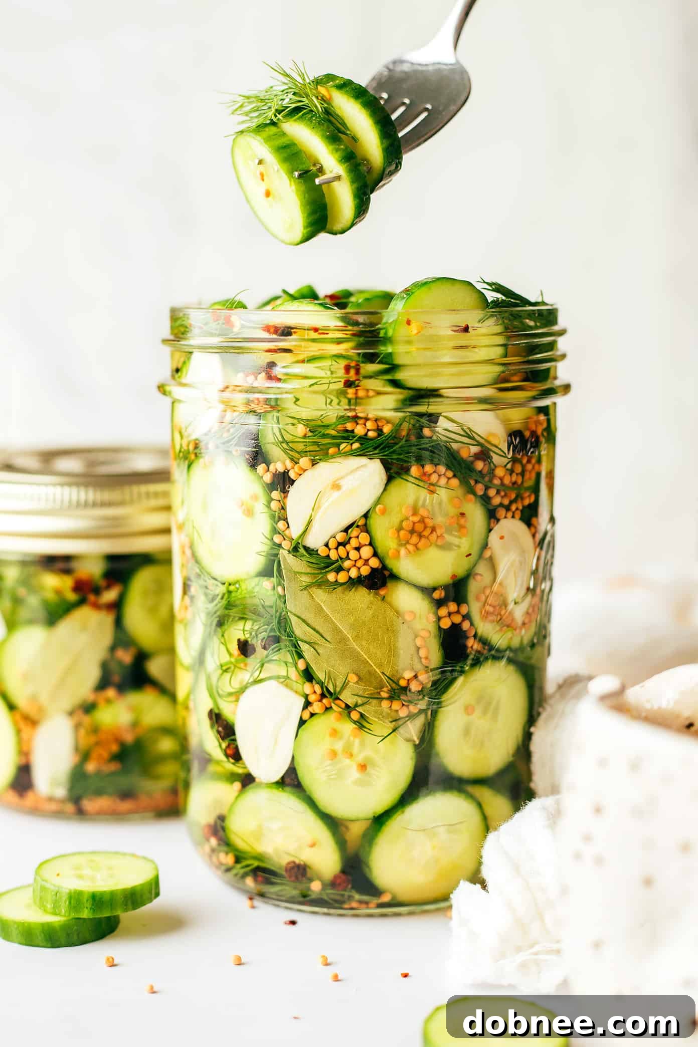 A hand pulling a pickle out of a jar with tongs