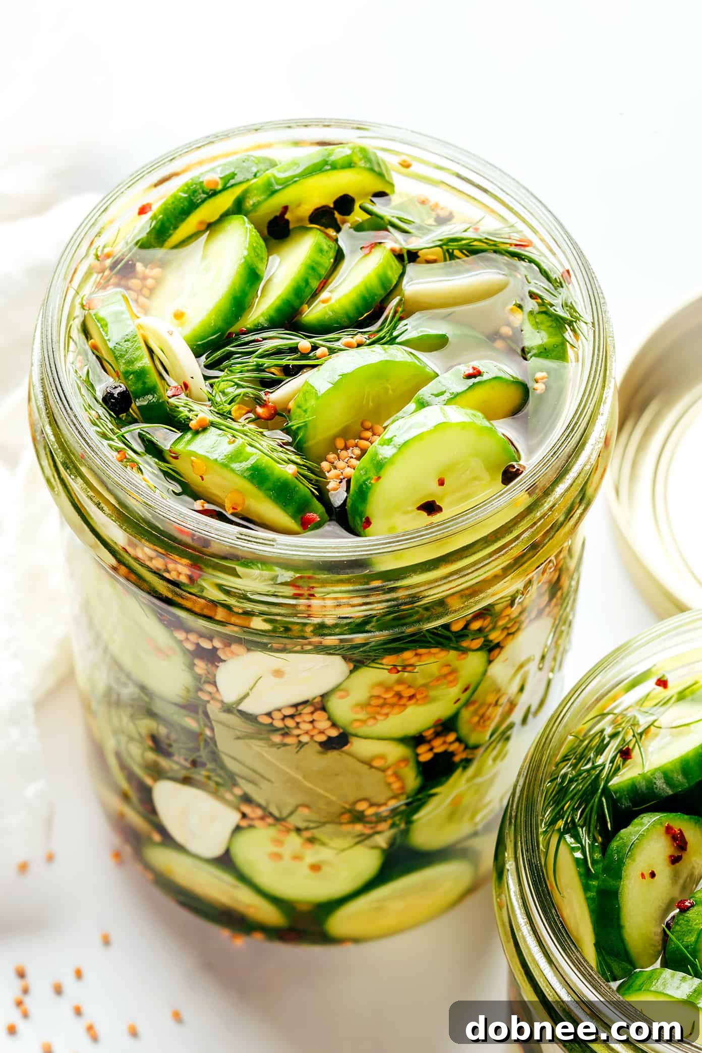 Seven different jars of pickles in a variety of sizes and shapes