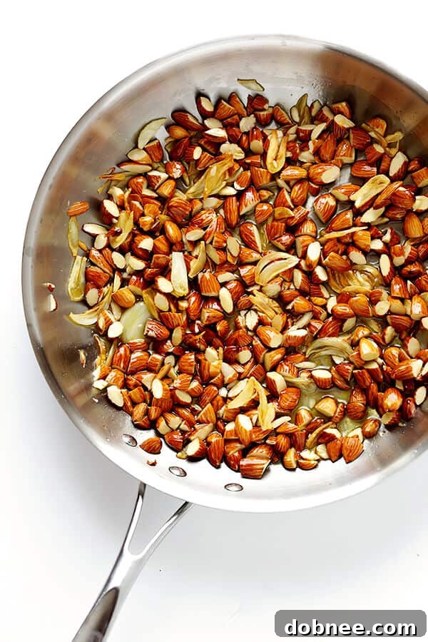 Sliced garlic cloves sautéing in olive oil in a pan, a fragrant base for the Lemon Basil Spaghetti with Almonds. | gimmesomeoven.com