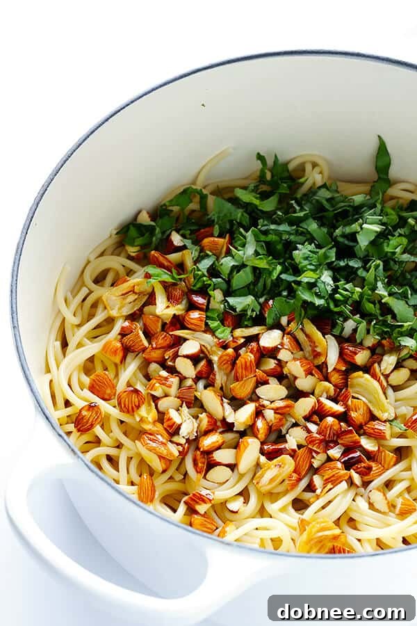 Toasted almonds and lemon juice added to the sautéed garlic and olive oil mixture in a pan, creating a zesty and nutty sauce base. | gimmesomeoven.com