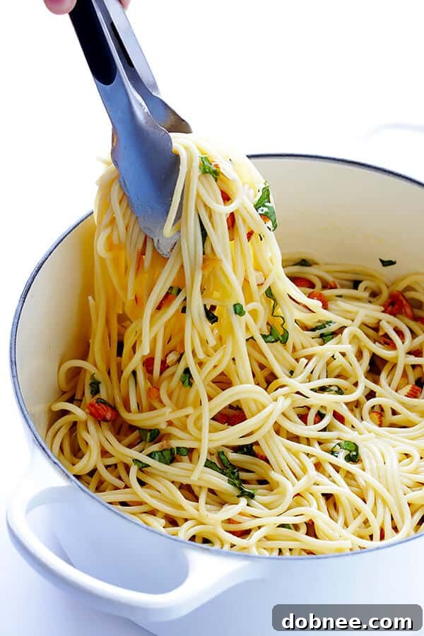 Cooked spaghetti tossed with the garlic, lemon, and almond mixture, along with a generous handful of fresh basil leaves, ready to be combined for a flavorful meal. | gimmesomeoven.com