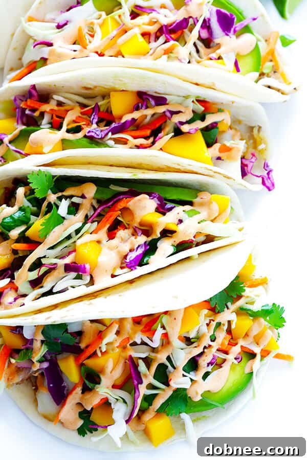 Flaky white fish tacos with a vibrant mango slaw and creamy chipotle lime sauce, perfect for a quick and flavorful meal.