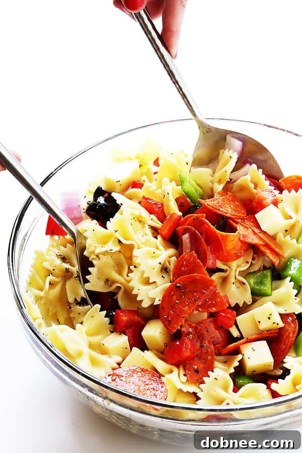 All the colorful and flavorful ingredients of the Pizza Pasta Salad are thoroughly tossed together with the homemade Italian vinaigrette, ensuring every bite is a delicious medley.