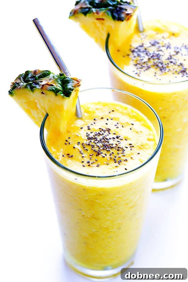 A vibrant yellow pineapple smoothie in a glass, garnished with fresh pineapple and chia seeds, suggesting health and deliciousness.