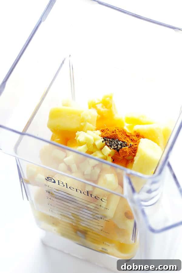 Ingredients for the Feel-Good Pineapple Smoothie, including pineapple, orange, ginger, turmeric, and chia seeds, laid out on a kitchen counter.