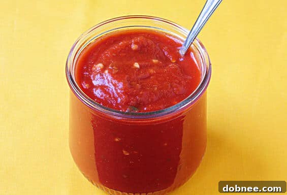 Delicious homemade pizza sauce in a bowl, ready to be spread on pizza, showcasing its rich red color and smooth texture.