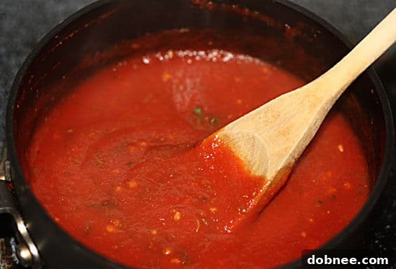 Closeup of homemade pizza sauce gently simmering in a small saucepan, steam rising, highlighting the cooking process and vibrant ingredients.