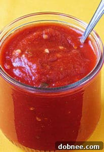 Perfect homemade pizza sauce in a jar, ready for use, with fresh basil leaves for garnish.