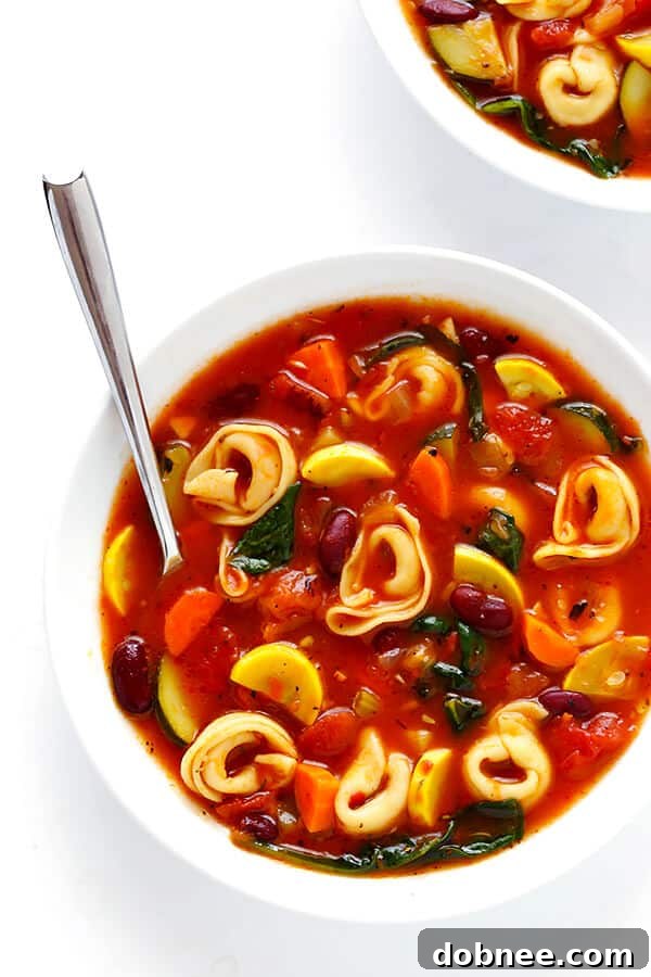 A close-up of a large pot of Tortellini Minestrone simmering on the stove, showing the vibrant broth, mixed vegetables, and the moment before adding the tortellini. Evokes warmth and homemade goodness.