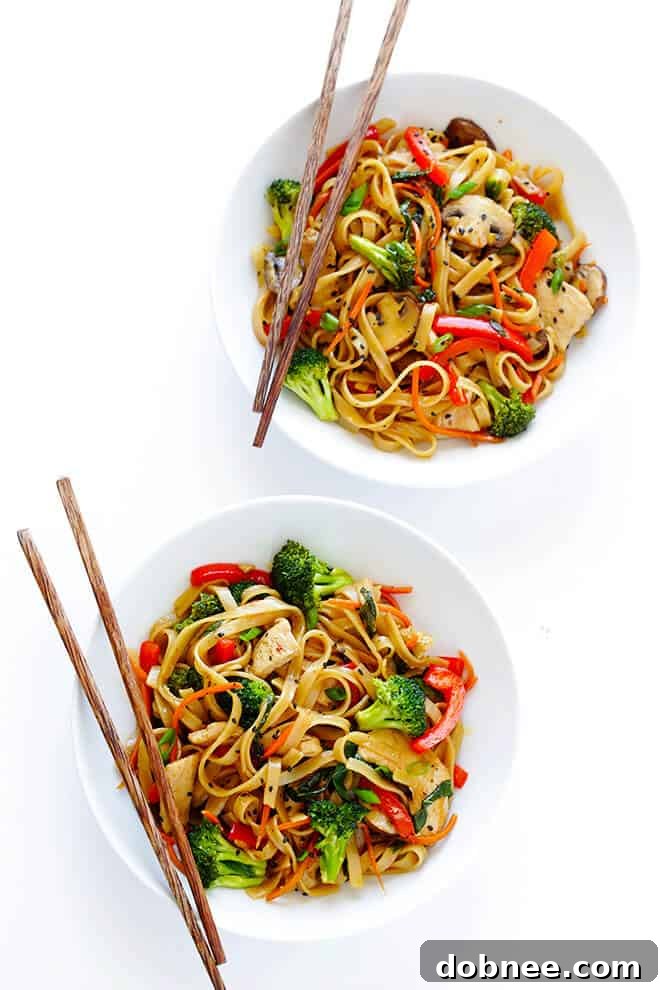 Garnishing Sesame Chicken Noodle Stir-Fry with Green Onions and Sesame Seeds
