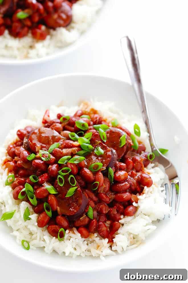 A large serving of slow cooker Red Beans and Rice served over fluffy white rice, garnished with fresh green onions.