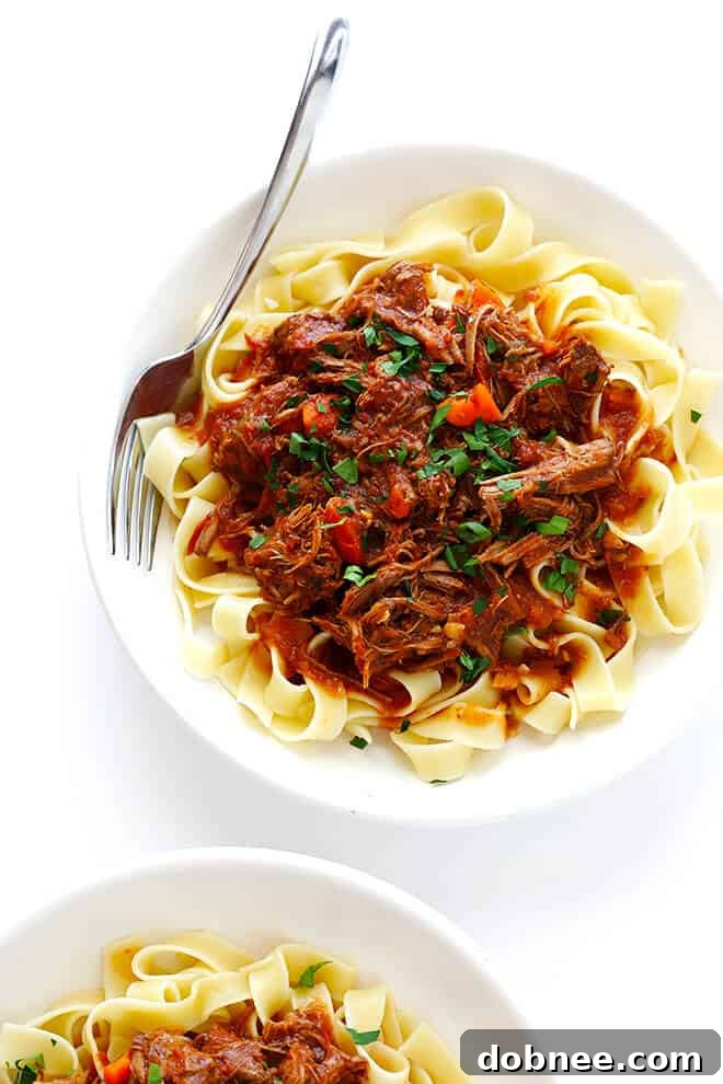 A beautifully plated dish of Slow Cooker Beef Ragu with pappardelle, topped with Parmesan and fresh parsley.