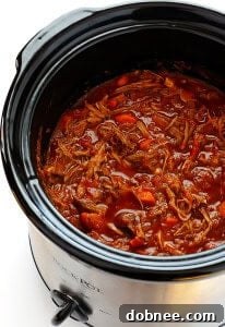 Delicious Slow Cooker Beef Ragu served over pappardelle pasta, garnished with fresh parsley and Parmesan cheese.