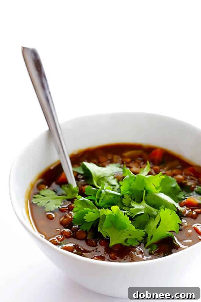 Close up view of a spoon scooping into the rich, aromatic Slow Cooker Curried Lentil Soup, highlighting its hearty texture and delicious appeal.