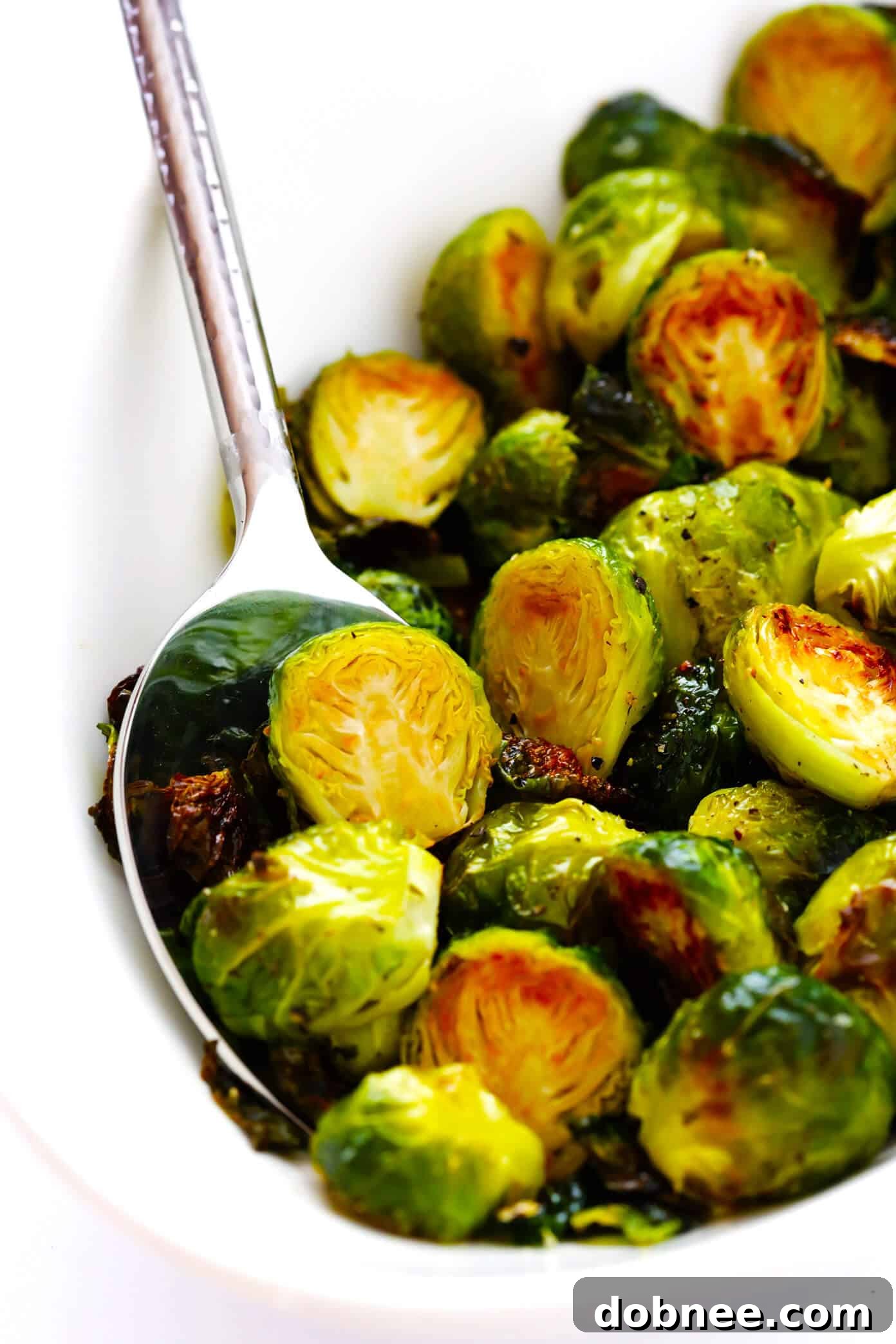 A serving bowl filled with hot, freshly roasted Brussels sprouts, garnished with extra seasoning, ready to be enjoyed.