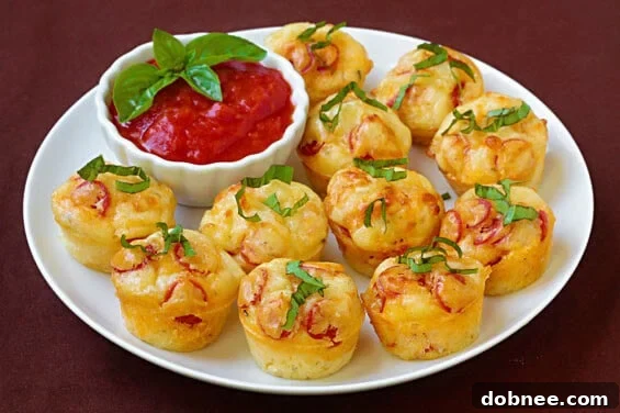Delicious golden-brown pepperoni pizza puffs arranged on a white plate, garnished with fresh basil. A perfect appetizer or snack.