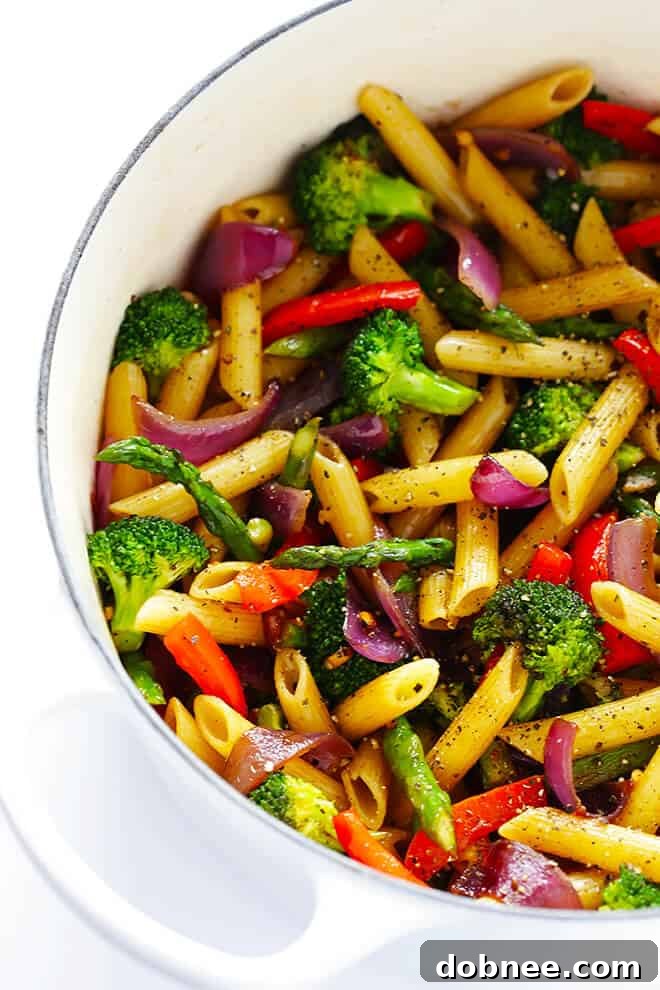 Simple Balsamic Garden Pasta 2 A vibrant bowl of Balsamic Veggie Pasta, showcasing fresh penne, sautéed asparagus, red bell peppers, broccoli, and red onion, glistening with balsamic vinaigrette and topped with Parmesan cheese.