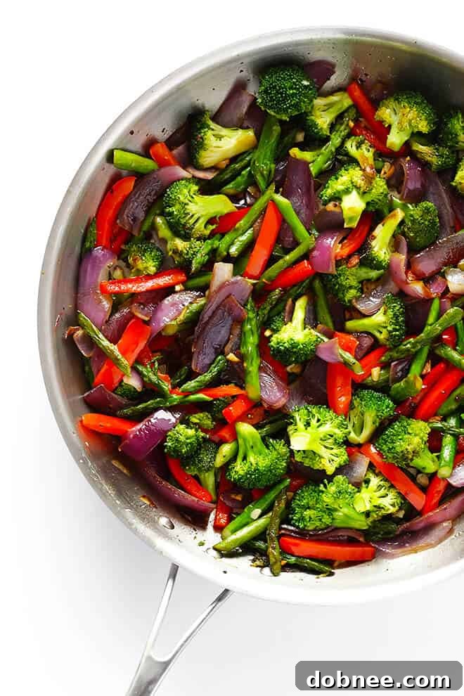 Simple Balsamic Garden Pasta 4 A hand holding a fork twirling Balsamic Veggie Pasta, showing the rich coating of sauce and colorful vegetable medley including red peppers, broccoli, and asparagus.
