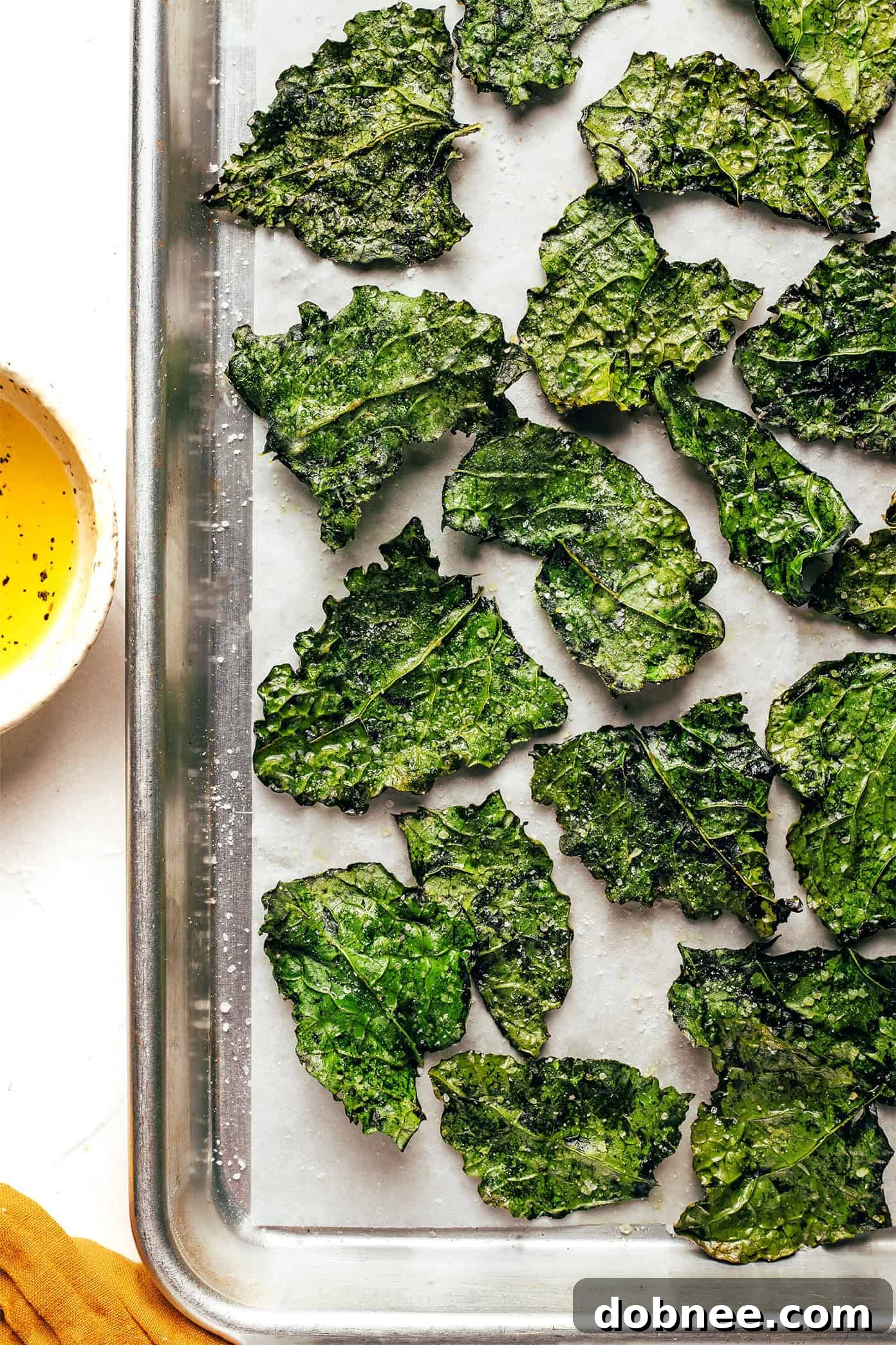 A perfectly baked, crispy batch of golden-green kale chips, artfully arranged and ready to be enjoyed as a healthy, savory snack.