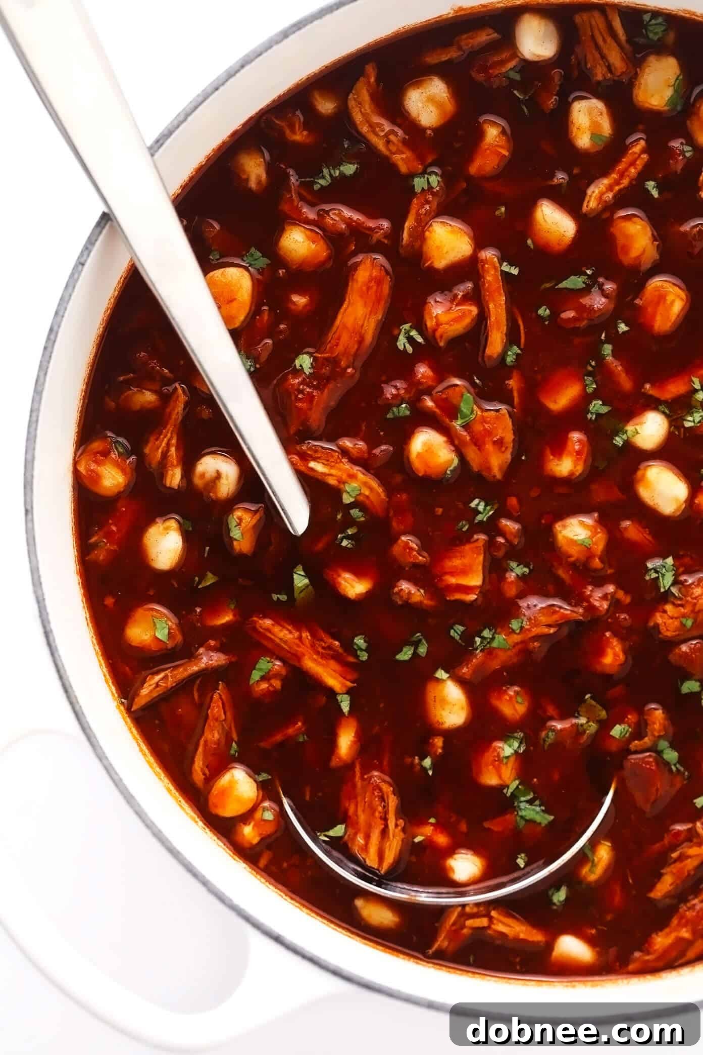 A large pot of simmering Pozole Rojo, rich with tender pork and plump hominy, ready for serving after slow cooking