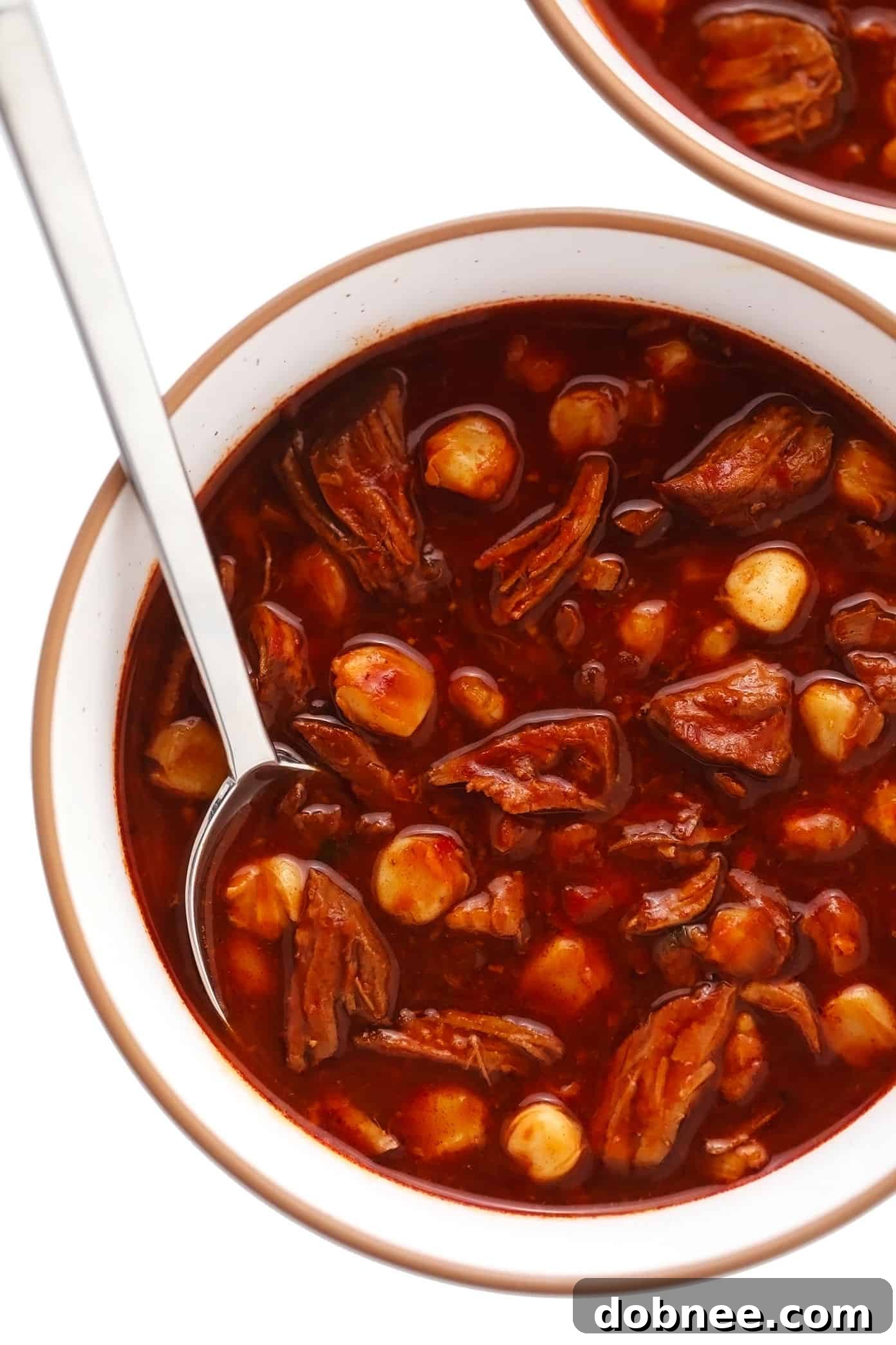 A serving bowl of unadorned Pozole Rojo, showing the rich red broth, tender pork, and hominy, perfectly cooked and waiting for fresh toppings