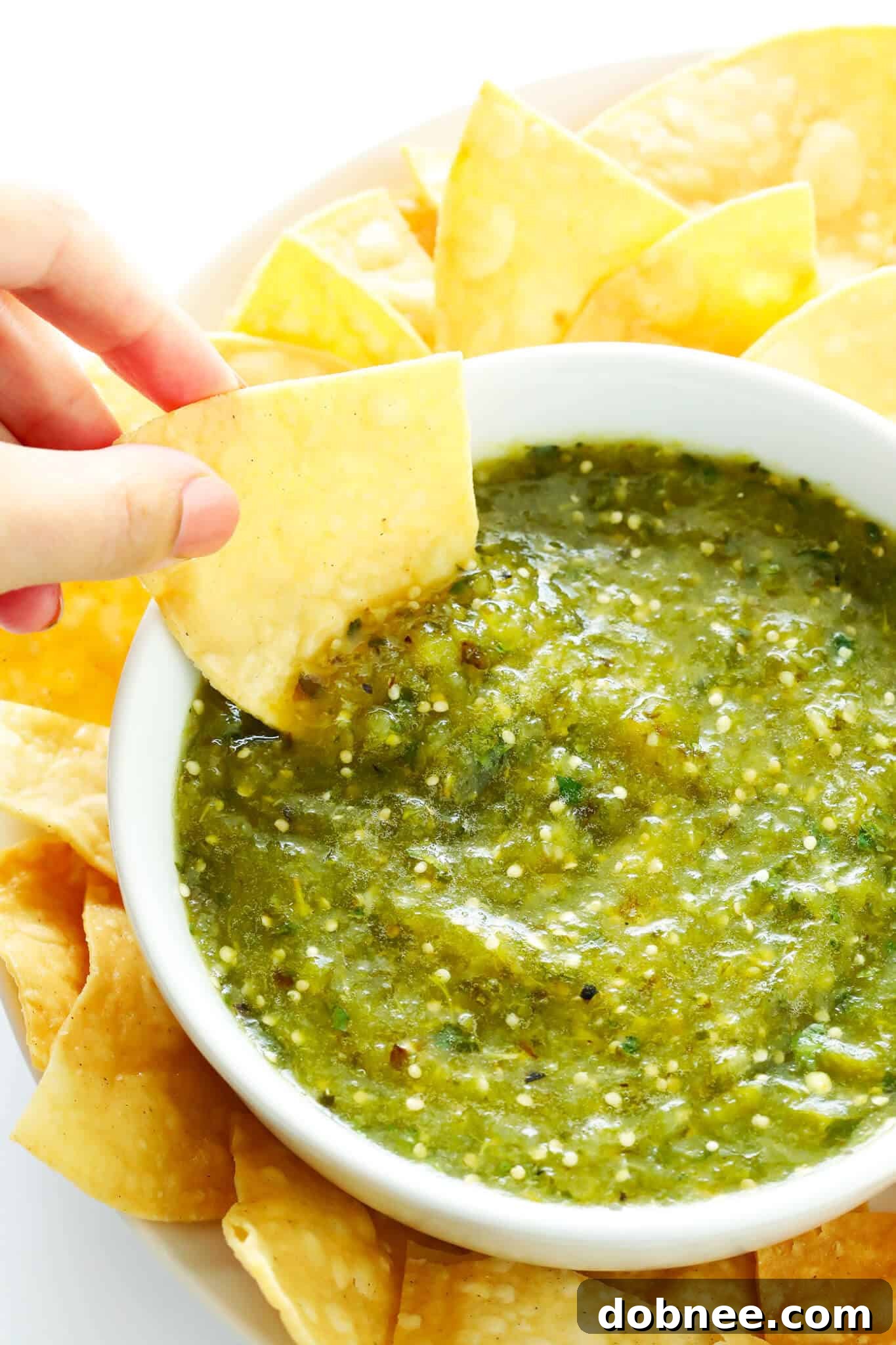 A beautifully presented bowl of homemade roasted salsa verde, surrounded by tortilla chips, ready for a gathering or a delicious snack. This versatile sauce is a staple for Mexican cuisine.