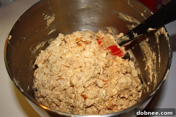 Scooped cookie dough with apricots and white chocolate on a baking sheet, ready for the oven
