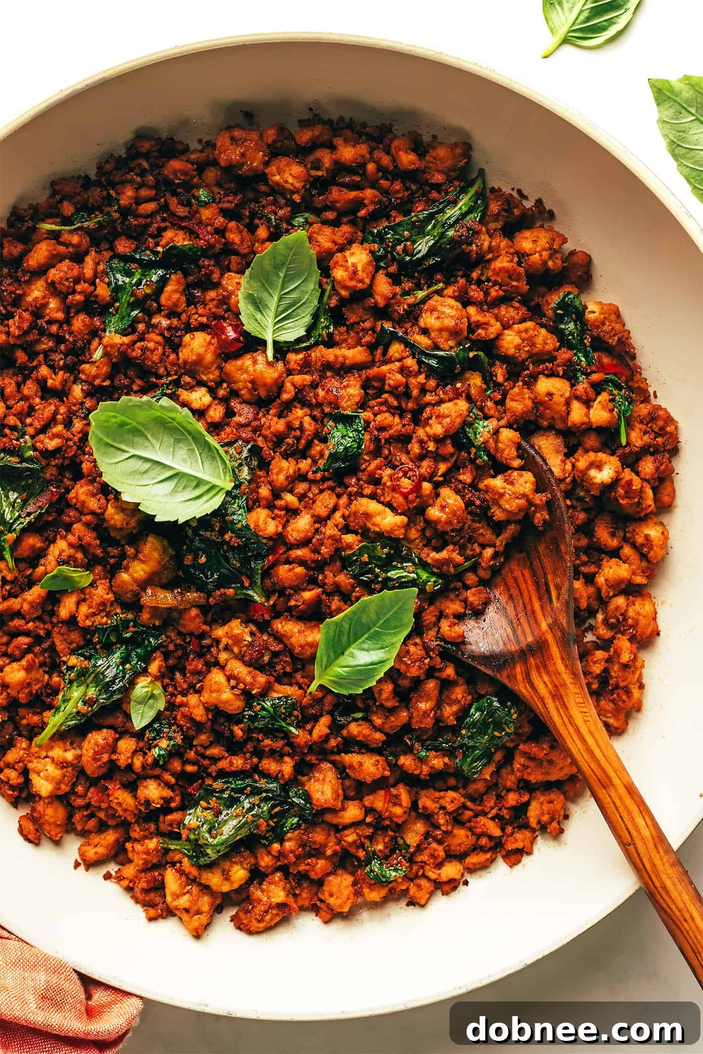 A close-up shot of ground chicken being stir-fried in a hot pan, demonstrating the browning process before other ingredients are added for a Thai Basil Chicken dish.