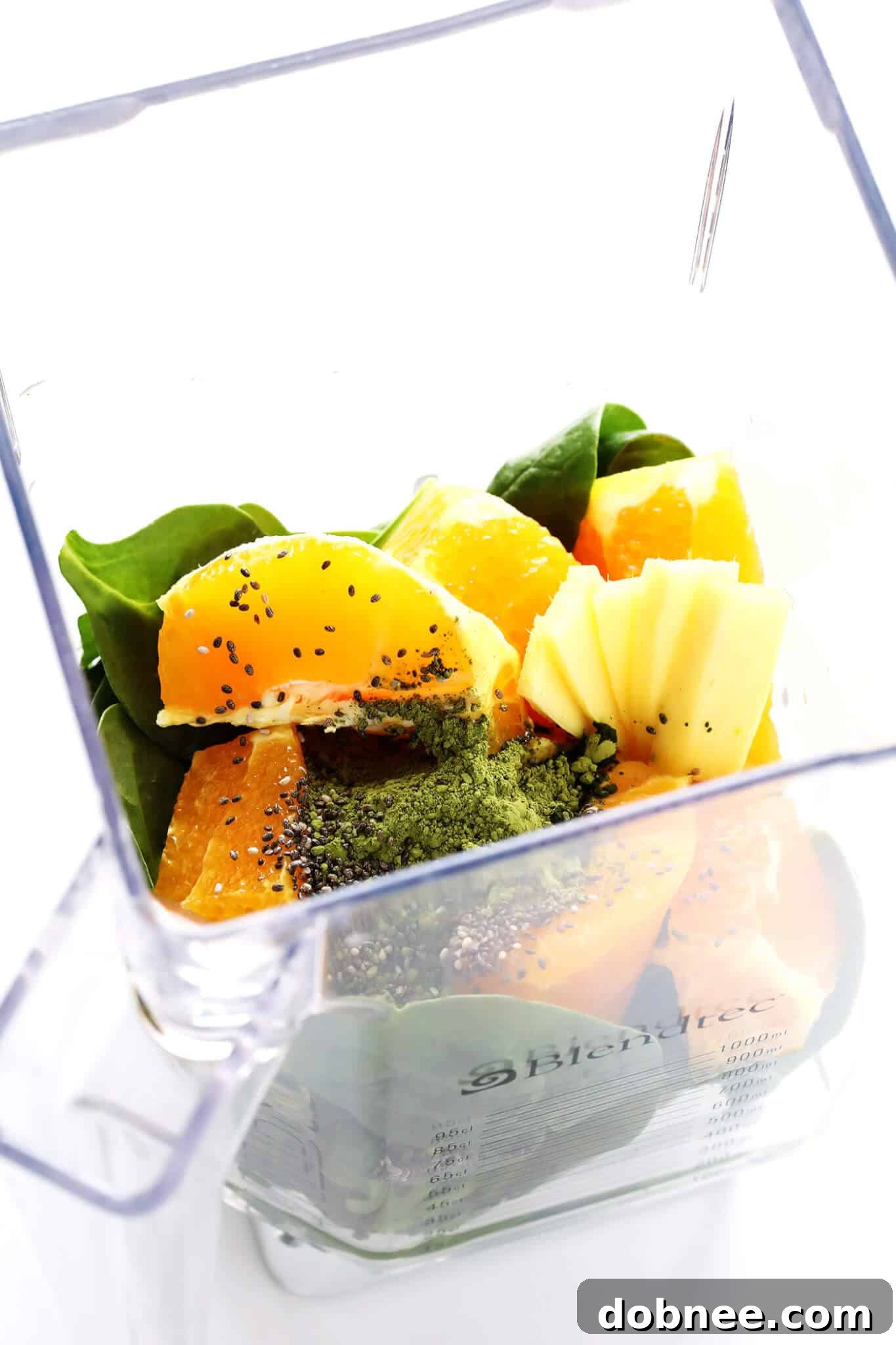 A high-speed blender filled with all the vibrant ingredients for the Matcha Ginger Green Smoothie before blending.