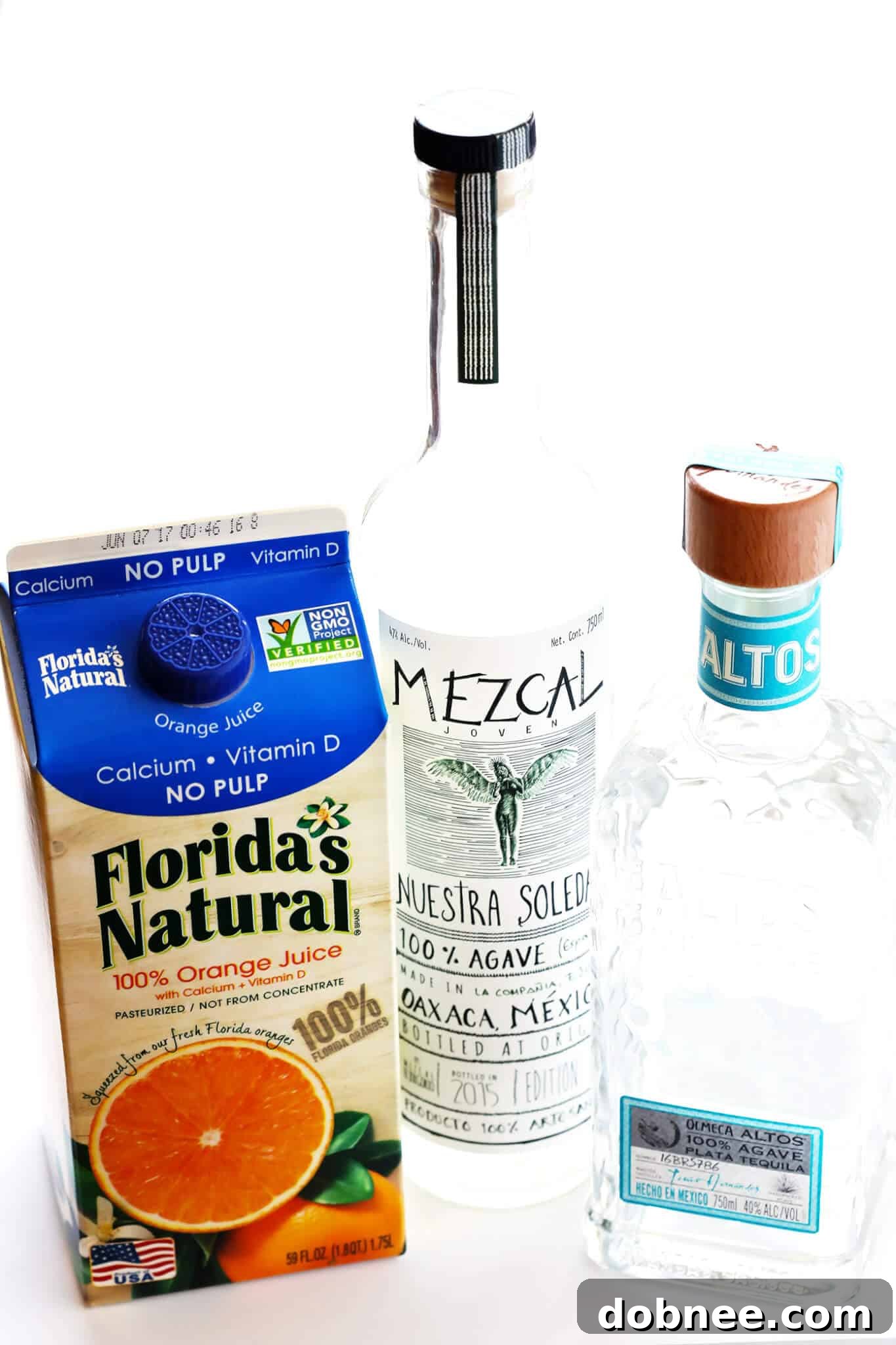 Agave Dawn Mimosa 3 Ingredients for Tequila Sunrise Mimosa laid out on a table: orange juice, tequila, champagne, grenadine, and limes.