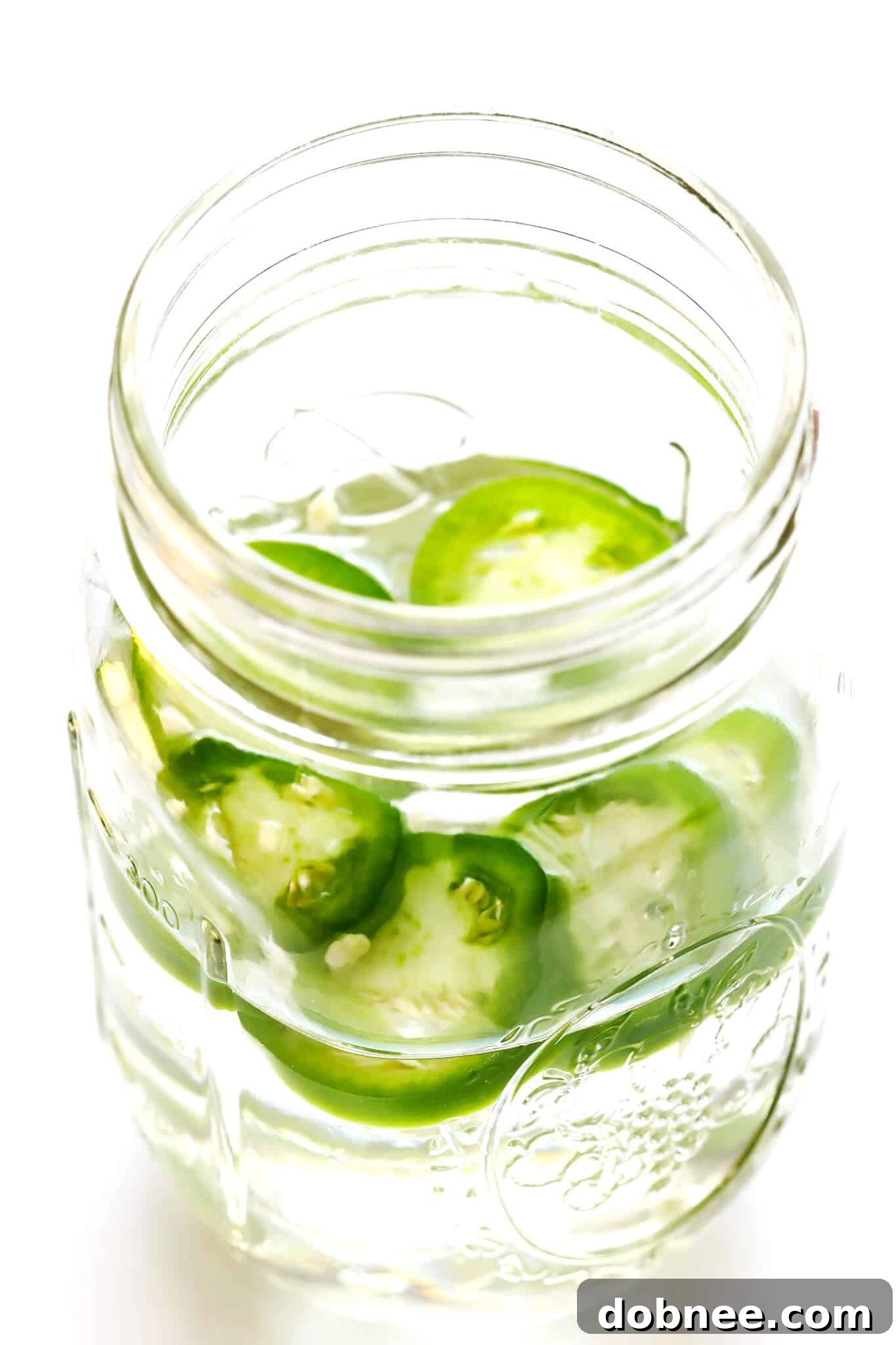 Agave Dawn Mimosa 4 Close-up of fresh jalapeño peppers next to a bottle of mezcal, suggesting a spicy infusion.