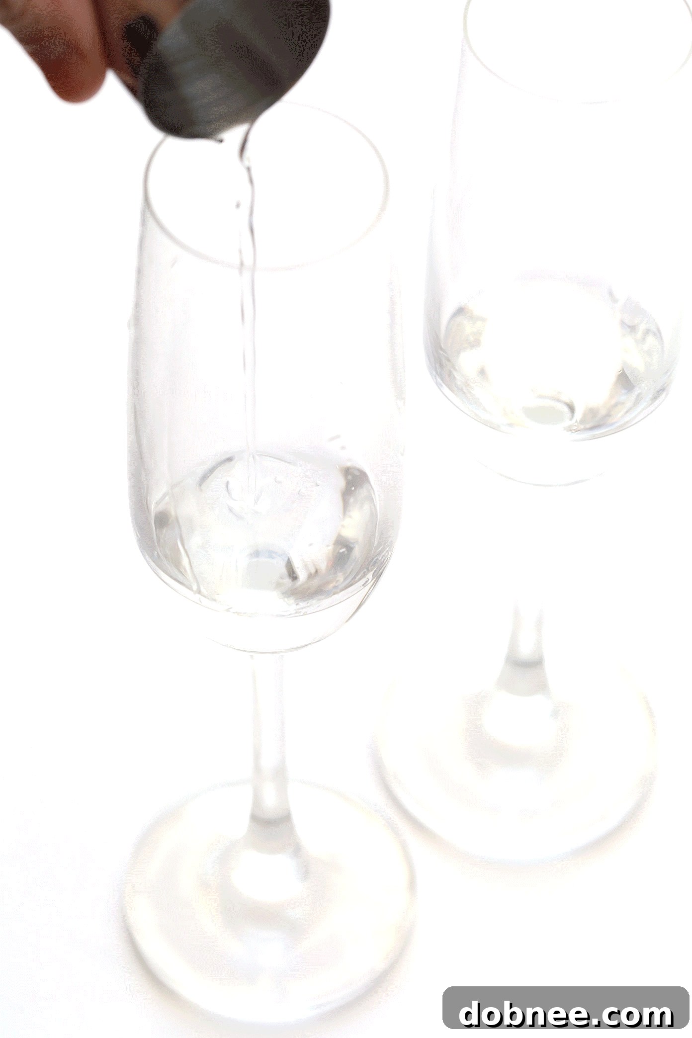 Agave Dawn Mimosa 5 A hand pouring orange juice into a champagne flute, part of the Tequila Sunrise Mimosa preparation.