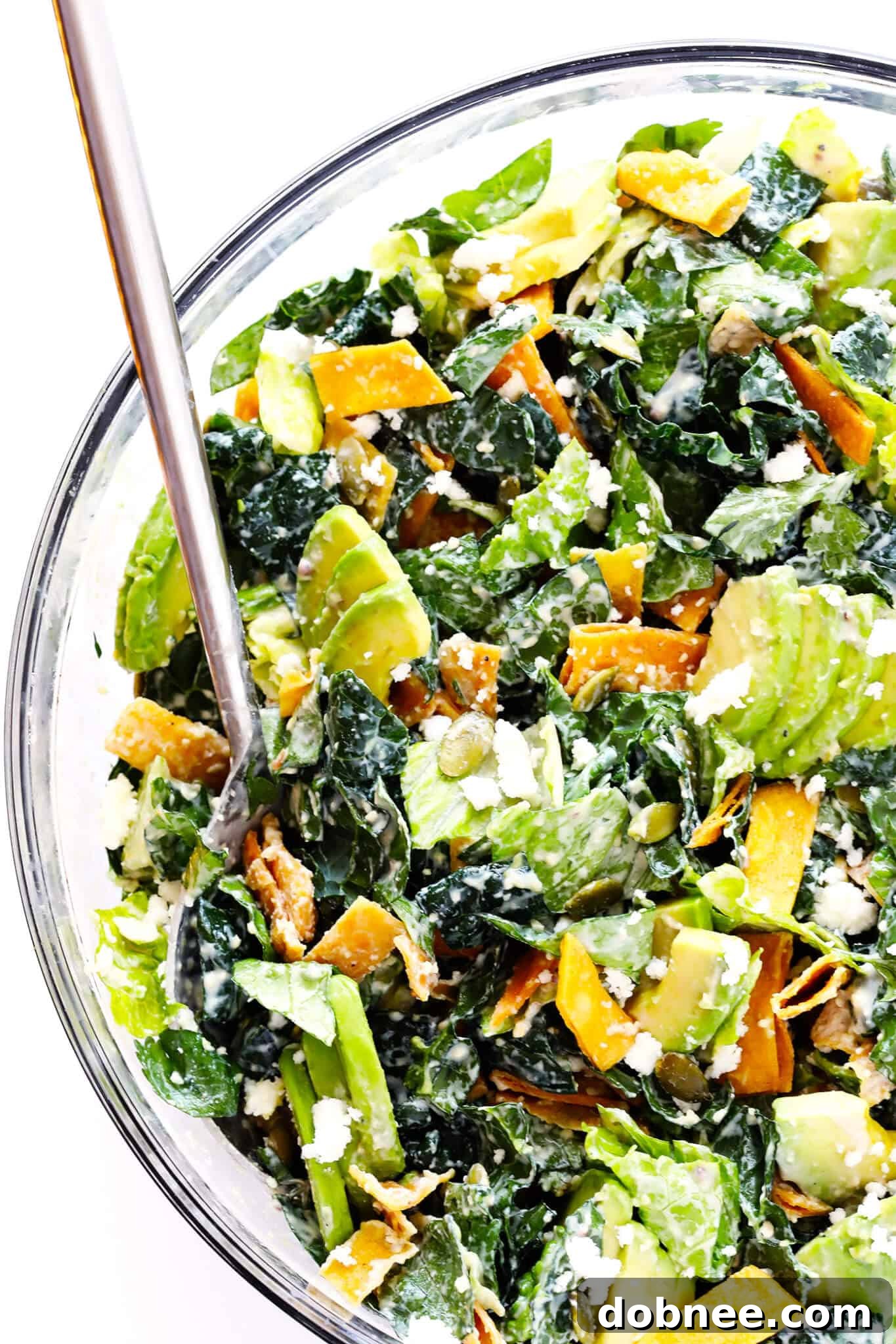 A vibrant Mexican Caesar Salad featuring crisp kale, Romaine lettuce, creamy avocado, crunchy tortilla strips, toasted pepitas, and zesty cotija cheese, all tossed in a healthy Greek Yogurt Caesar Dressing.