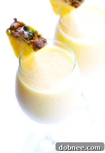 A glass of Tropical Mimosa Smoothie garnished with pineapple.