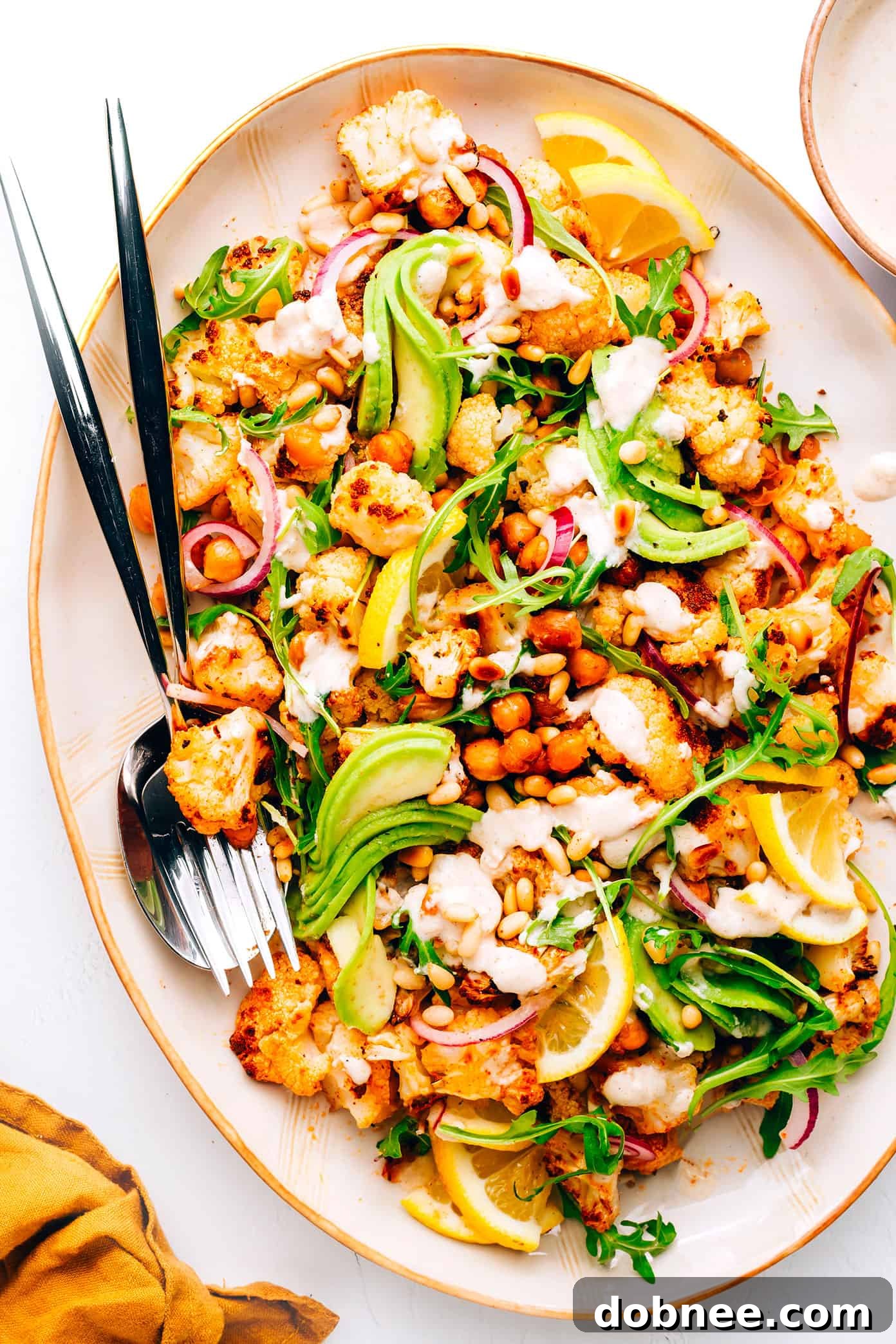 Vibrant roasted cauliflower and chickpea salad with fresh arugula and avocado in a large bowl