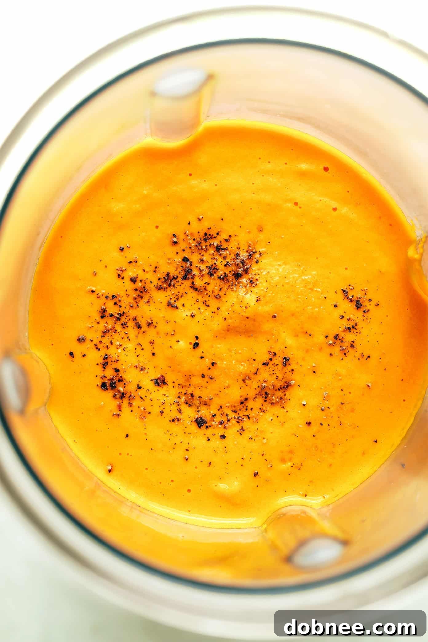 Close-up of the carrot ginger dressing being poured from a blender into a jar