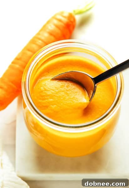 A jar of homemade carrot ginger dressing with a fresh carrot garnish