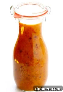 Delicious Honey Chipotle Salad Dressing in a glass jar, next to a spoon with dressing and a small bowl of chipotles in adobo.