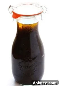 A vibrant homemade balsamic vinaigrette in a clear glass bottle, ready to be drizzled over fresh ingredients.