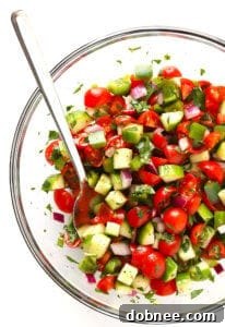 A vibrant bowl of Quick Israeli Salad with finely diced cucumbers, tomatoes, bell peppers, fresh herbs, and a lemon wedge.