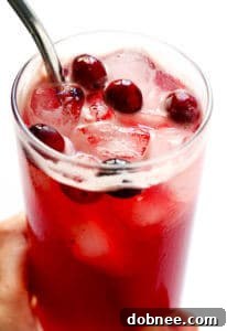Cranberry Bourbon Fizz cocktail in a glass with cranberries and rosemary.