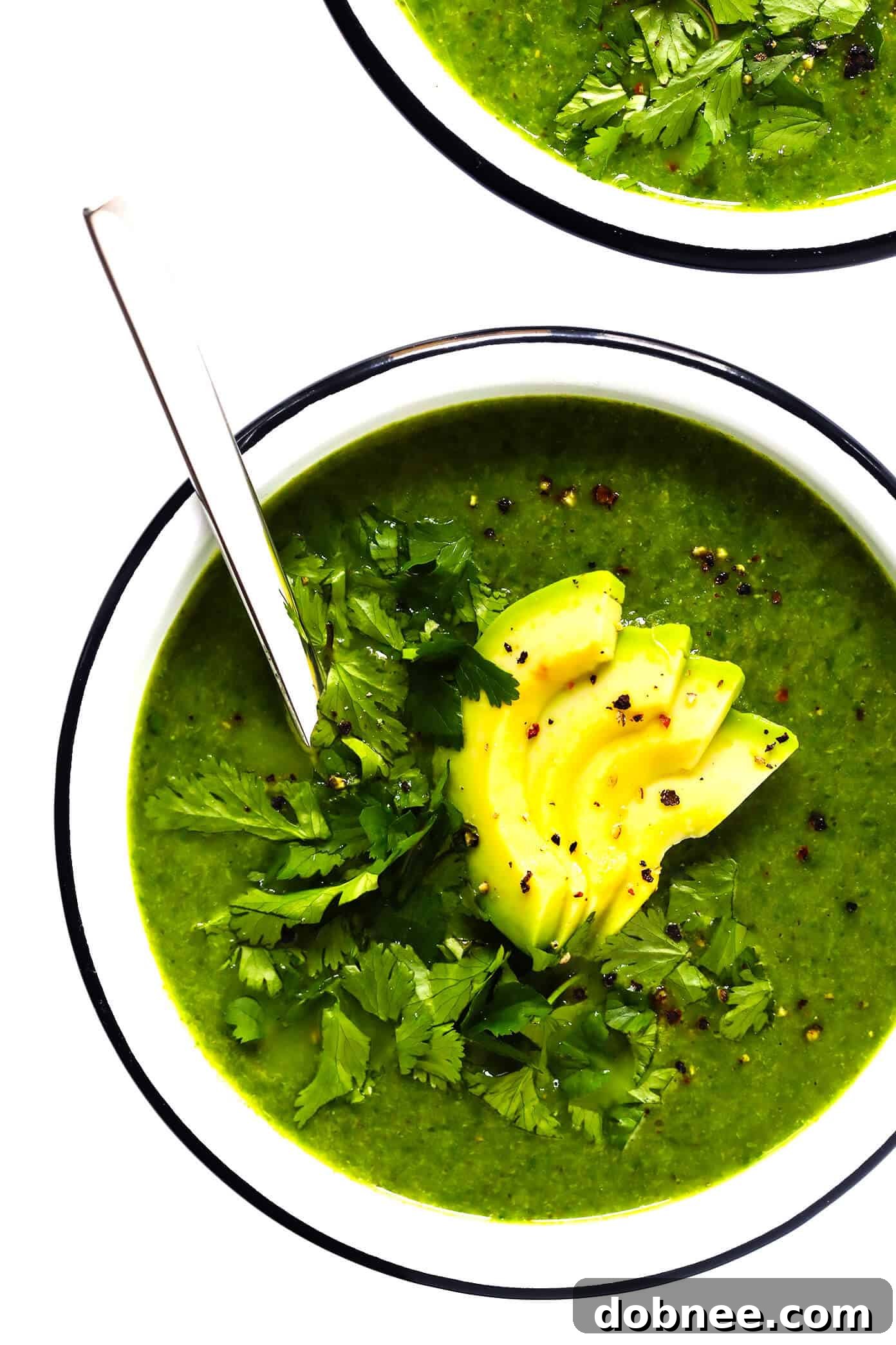 Creamy Green Goddess Soup with fresh avocado and cilantro in a white bowl