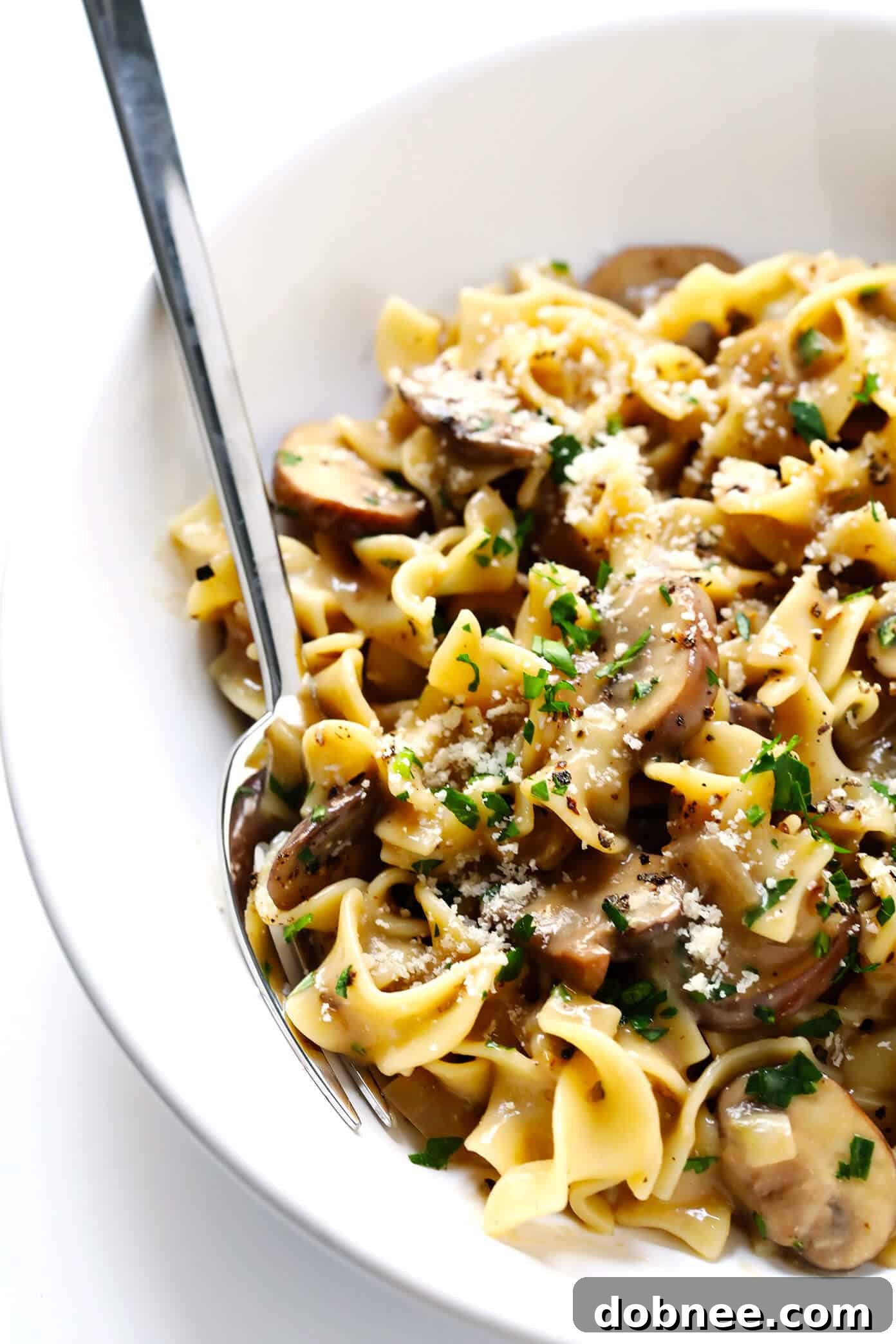 A bowl of Vegetarian Mushroom Stroganoff garnished with fresh parsley and black pepper, ready to be enjoyed.