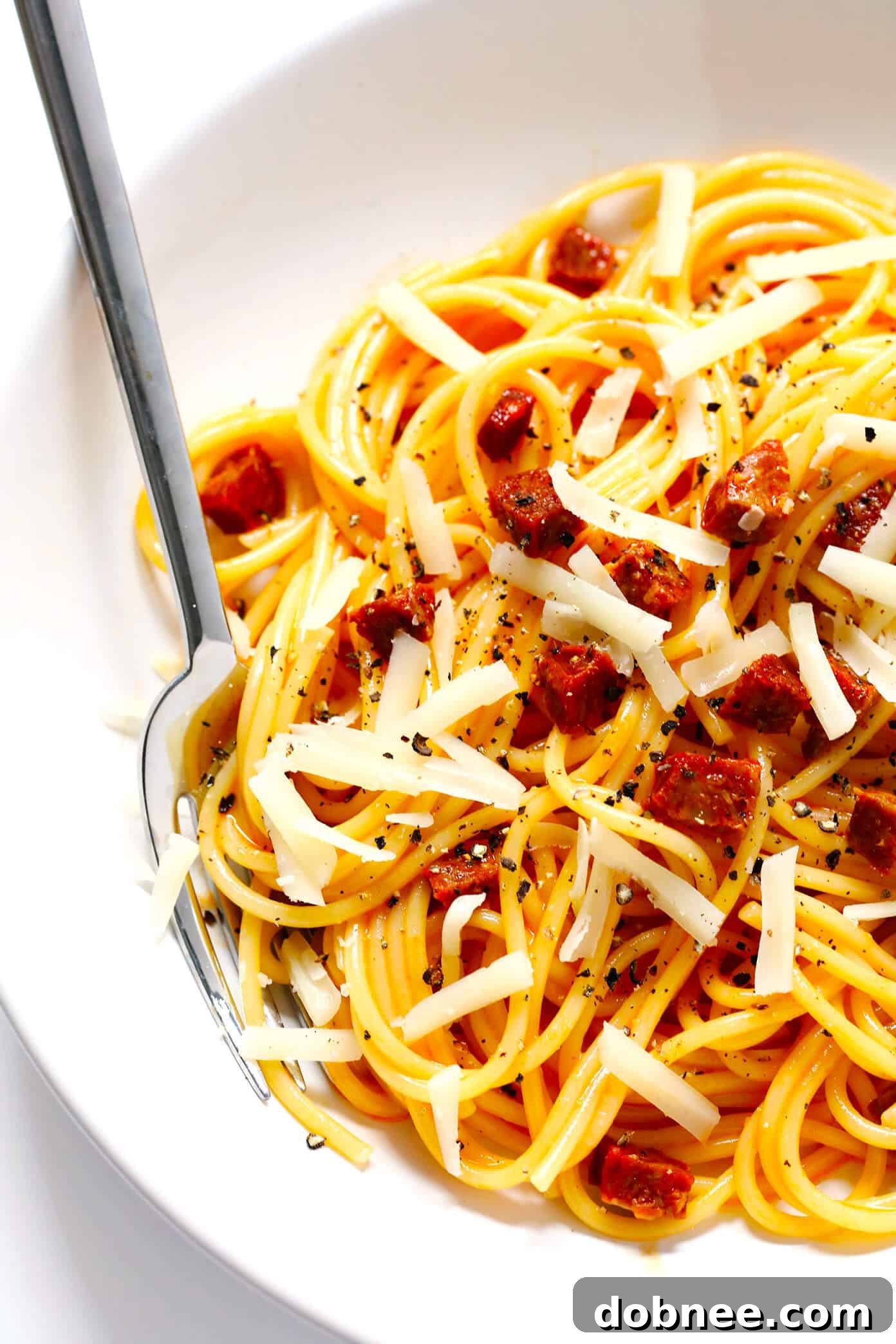 Final presentation of Spanish Chorizo Spaghetti Carbonara, garnished with fresh black pepper and Manchego cheese