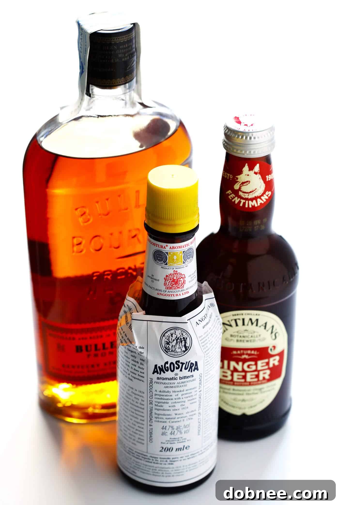 Essential ingredients for a Horsefeather Cocktail: bourbon, premium ginger beer, Angostura bitters, and fresh citrus